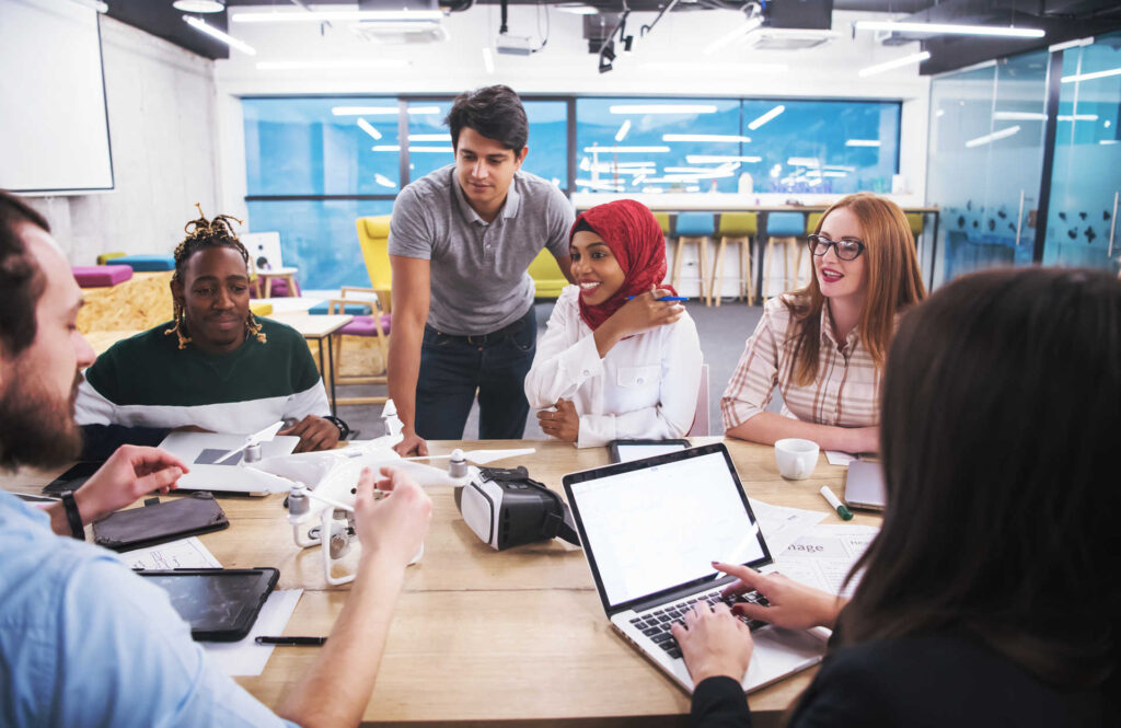 multiethnic business team learning about drone technology multiethnisches Startup-Unternehmensteam, das einen neuen Geschäftsplan bespricht und an Laptop und Tablet-Computer arbeitet, während es sich über die Drohnentechnologie für neue Geschäftsmöglichkeiten informiert