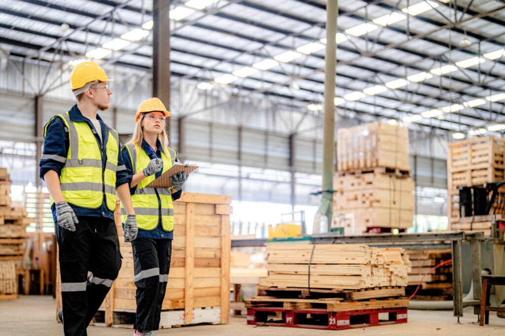 workers man and woman engineering walking and inspecting with wo Ein Arbeiter und eine Arbeiterin gehen durch eine Produktionshalle eines holzverarbeitenden Unternehmens.